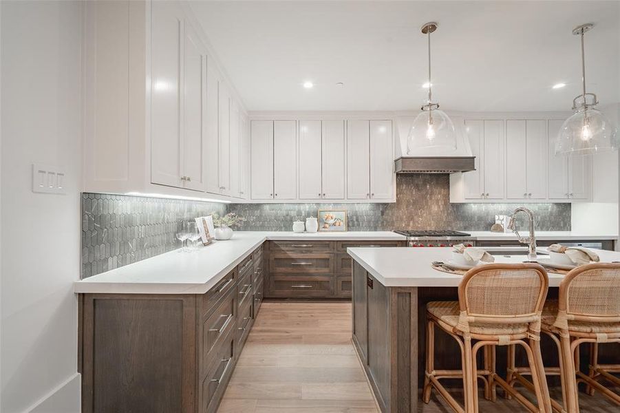 Kitchen featuring sink, white cabinetry, hanging light fixtures, a kitchen breakfast bar, and stainless steel gas stovetop