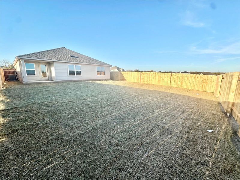 Back of property with a fenced backyard and roof with shingles