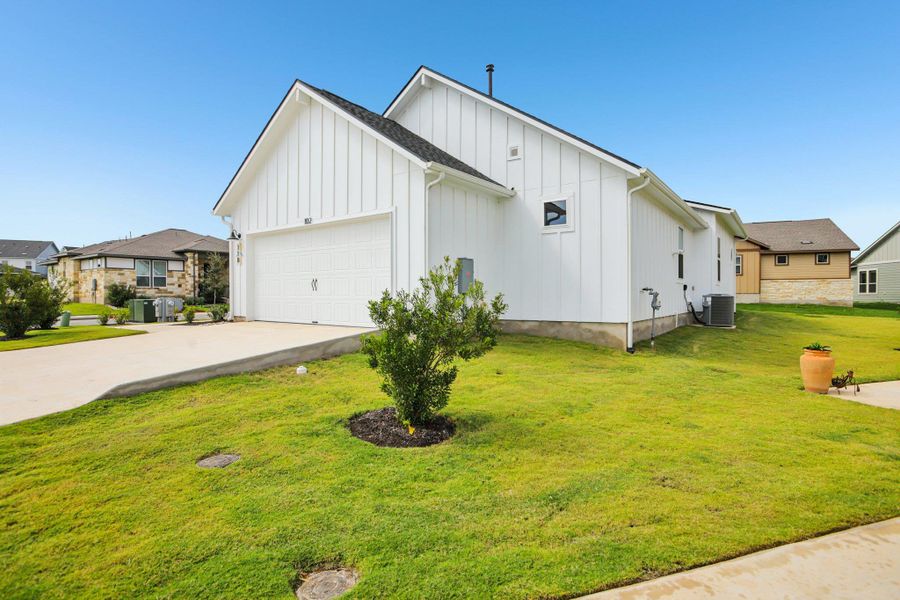View of property exterior featuring board and batten siding, concrete driveway, a yard, and a garage View of property exterior featuring board and batten siding, concrete driveway, a yard, and a garage