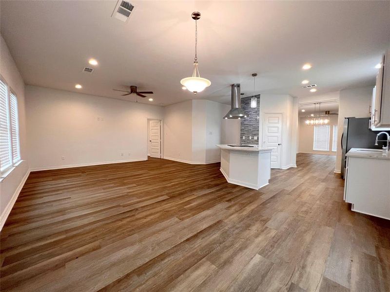 Family room and second dining room  with an open concept with kitchen featuring decorative light fixtures, exhaust hood, hardwood / wood-style floors, and ceiling fan