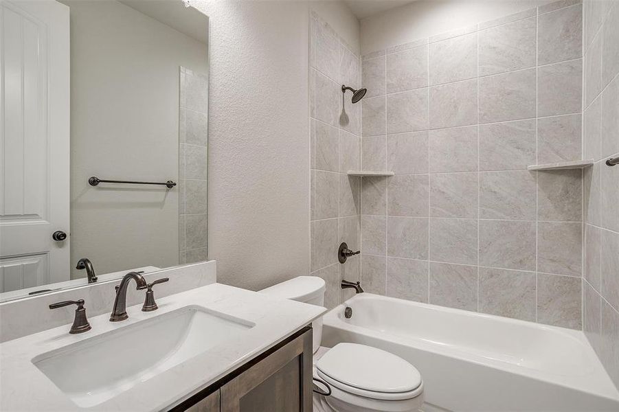 Full bathroom with vanity, tiled shower / bath, and toilet