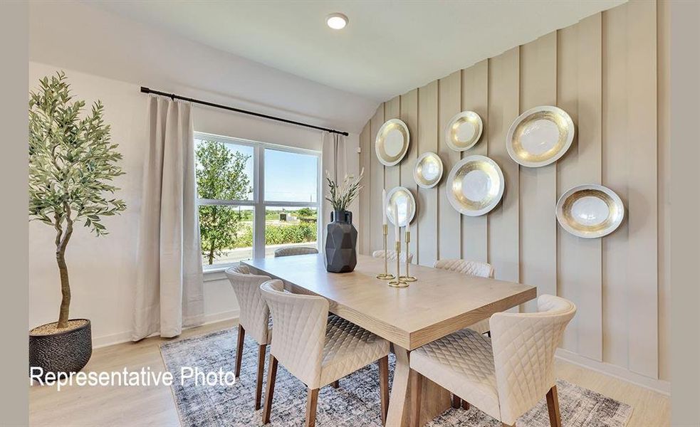 Dining space featuring light wood-finish flooring, a contemporary accent wall with vertical paneling, and a large window with white trim