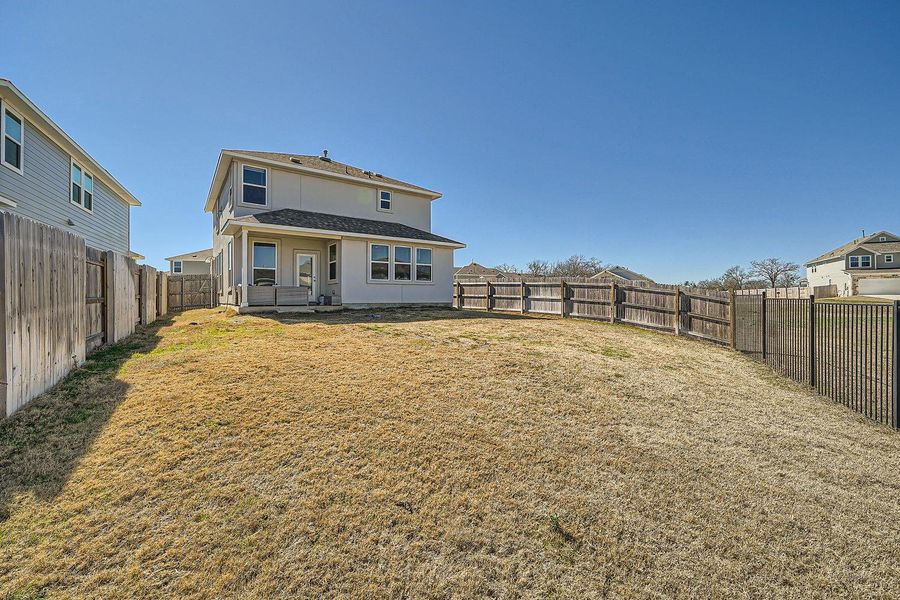 Back of house with a residential view, a fenced backyard, a lawn, and stucco siding