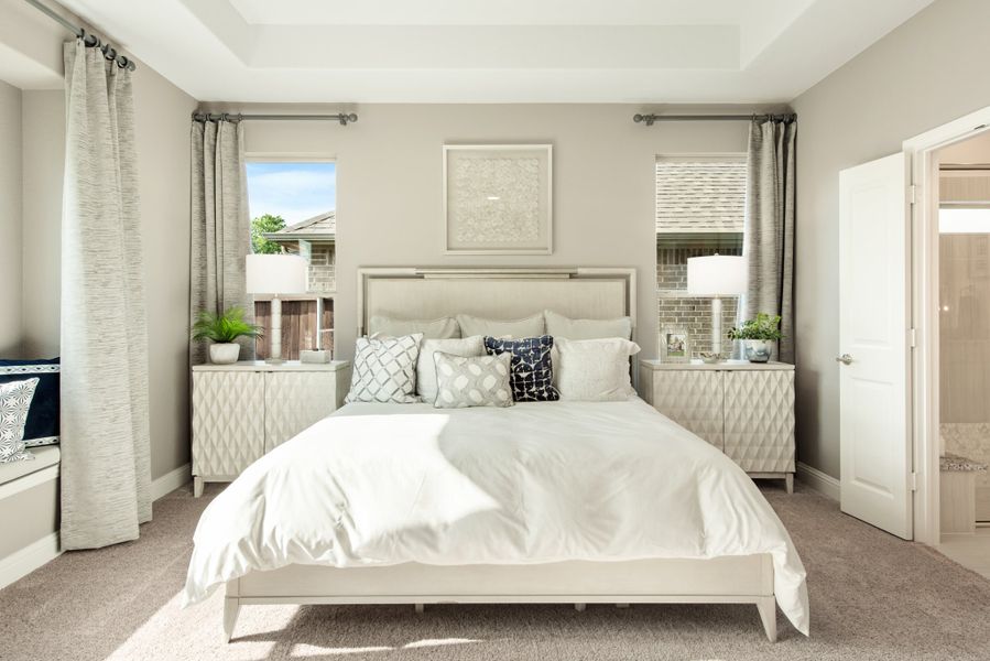 Master bedroom with king bed, tray ceiling, two windows with gray curtains, and matching nightstands