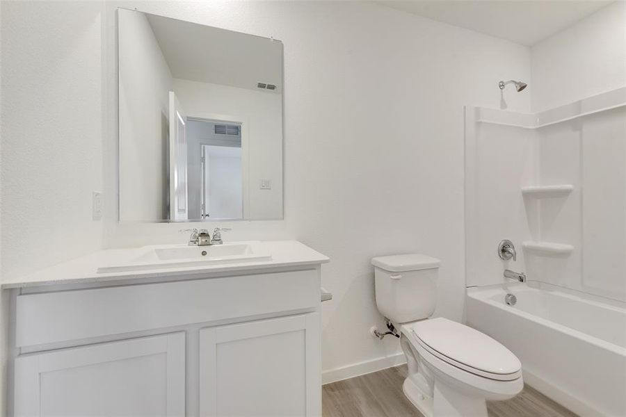 Full bathroom with hardwood / wood-style floors, vanity, bathtub / shower combination, and toilet