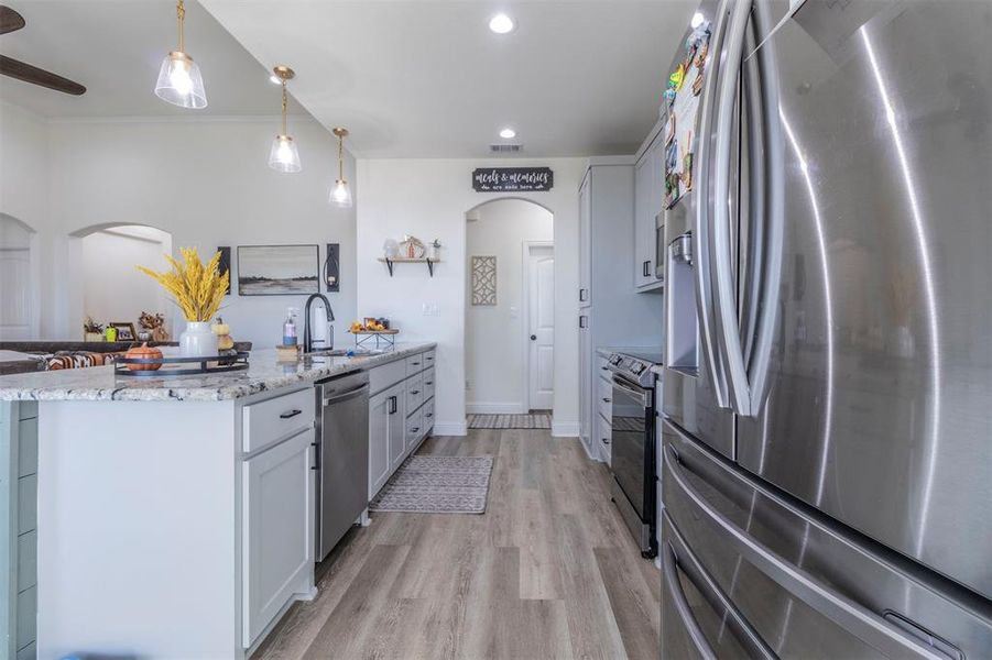 Kitchen with cabinets, sink, decorative light fixtures, and appliances with stainless steel finishes