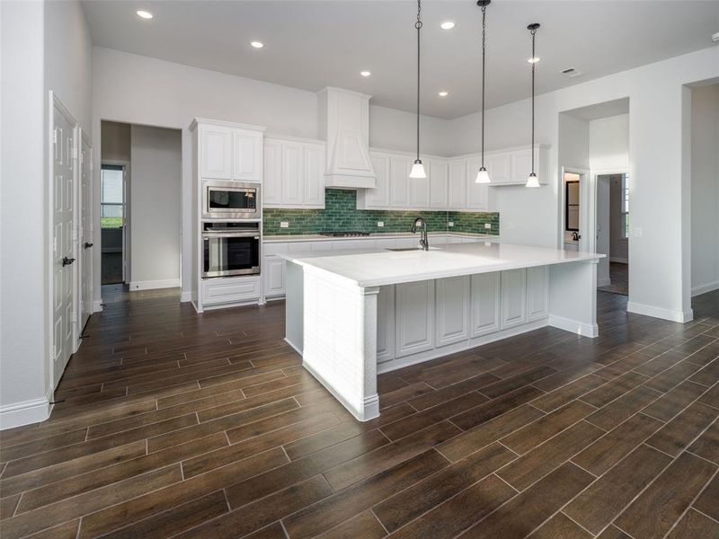 Kitchen with white cabinets, appliances with stainless steel finishes, a spacious island, recessed lighting, and backsplash