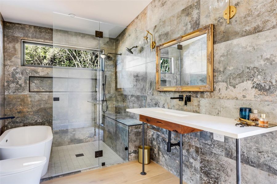 Full bath featuring a shower stall, tile walls, a soaking tub, and wood finished floors