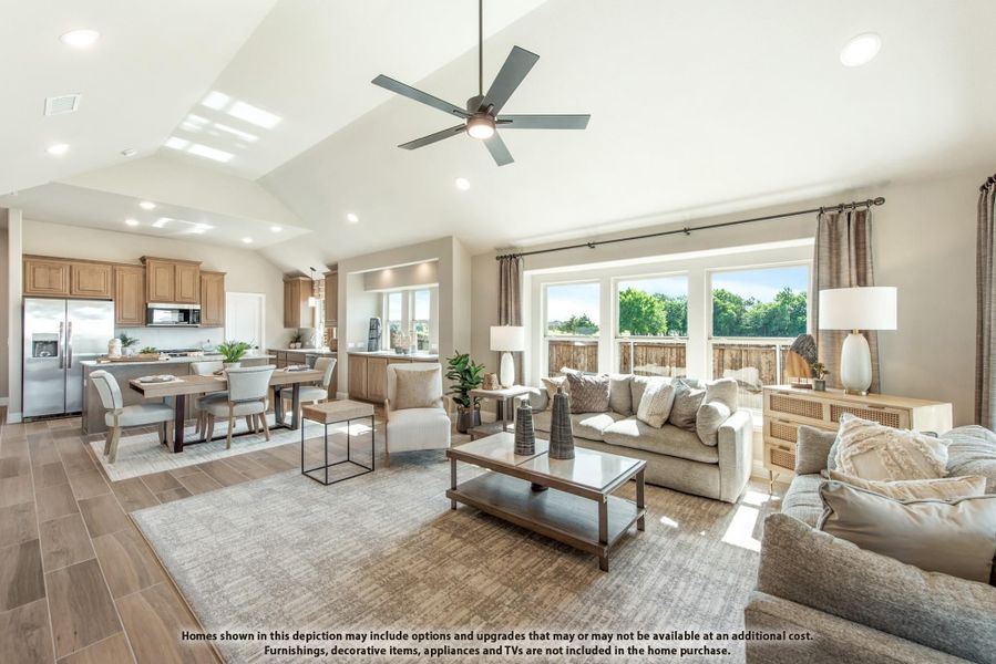 Open-concept living room with vaulted ceiling, ceiling fan, and views into dining area and kitchen