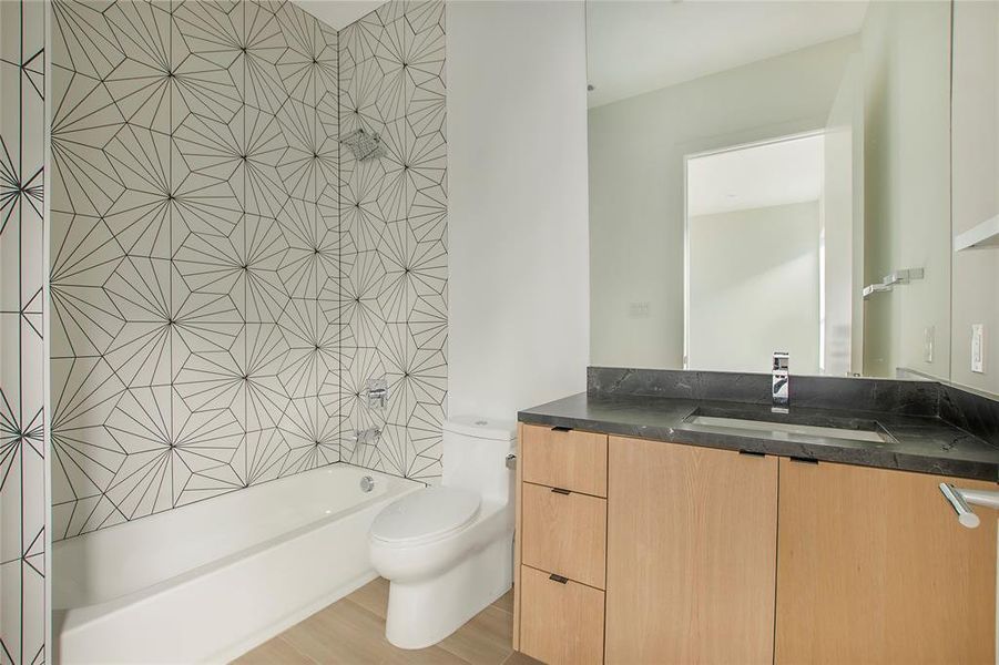 Full bathroom featuring toilet, vanity, tiled shower / bath combo, and hardwood / wood-style flooring