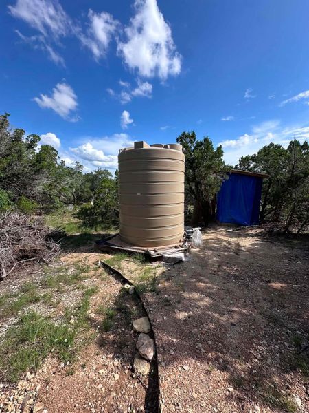 Essential water storage facility with a clear sky backdrop, surrounded by natural flora.