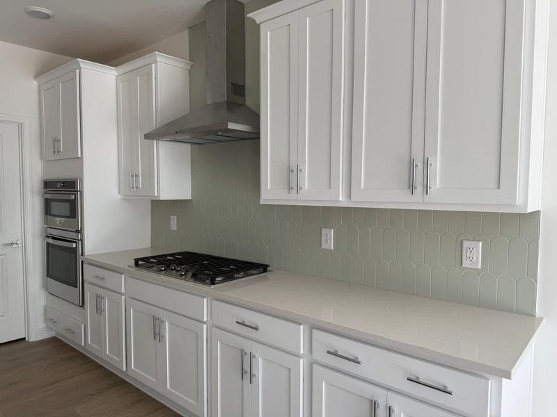 Kitchen featuring the AW Collection® Coastal - White cabinets and sea-glass tile backsplash. Kitchen featuring the AW Collection® Coastal - White cabinets and sea-glass tile backsplash.