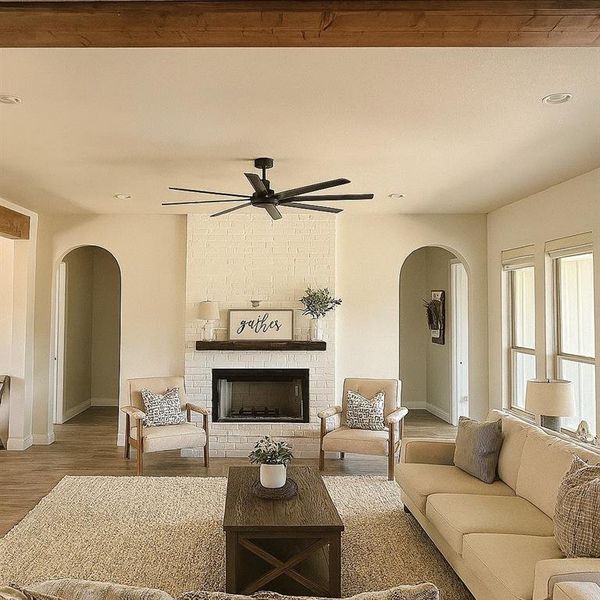 Living area featuring arched walkways, wood finished floors, a fireplace, ceiling fan, and recessed lighting Living area featuring arched walkways, wood finished floors, a fireplace, ceiling fan, and recessed lighting