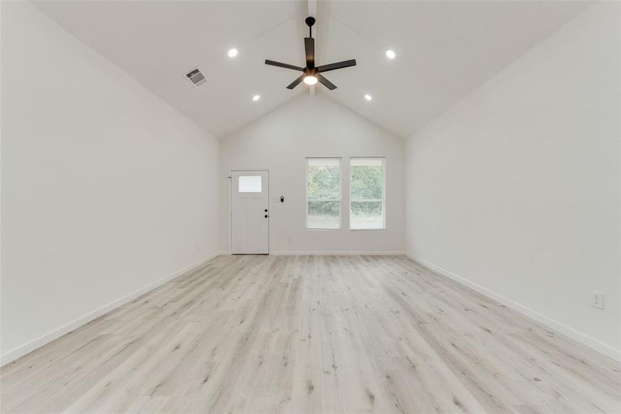 Unfurnished living room featuring high vaulted ceiling, ceiling fan, and light hardwood / wood-style floors