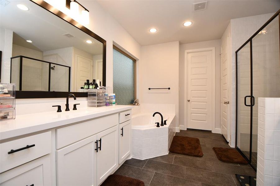 This Primary bathroom features a modern design with a large vanity and double sinks, a spacious glass-enclosed shower, and a separate bathtub. The room is well-lit with recessed lighting, and neutral tiles create a clean, elegant look.