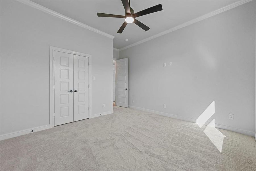 Unfurnished bedroom with ceiling fan, crown molding, light carpet, and a closet