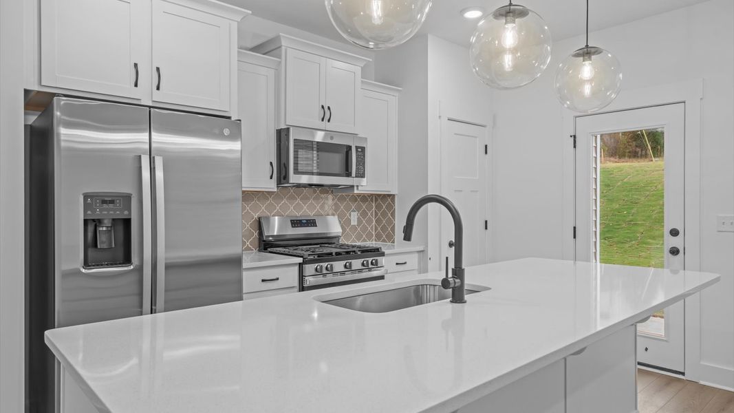 First-class kitchen with a spacious 9-foot island perfect for entertaining beneath designer pendant lighting First-class kitchen with a spacious 9-foot island perfect for entertaining beneath designer pendant lighting