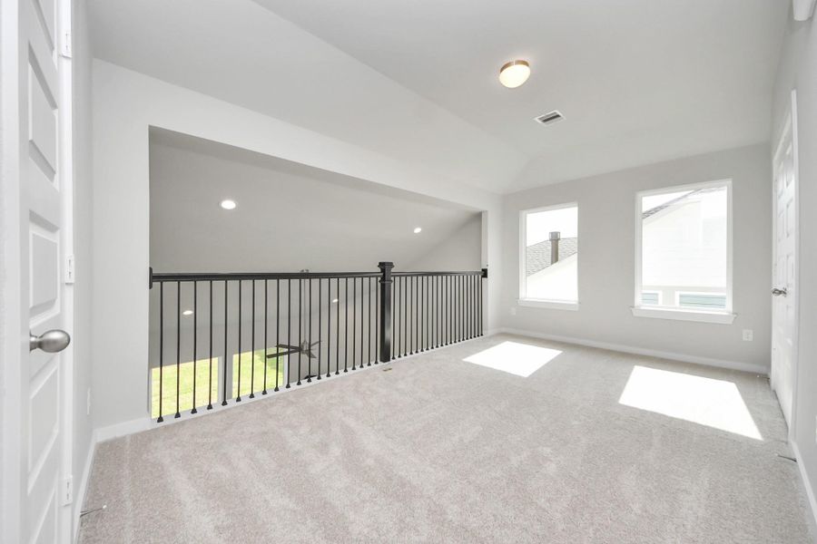 Come upstairs and relish a day of relaxation in this loft area! Ideal as an additional living space or game room, it boasts plush carpeting, high ceilings, custom paint, and windows that flood the area with abundant natural light. Sample photo of completed home with similar floor plan. Actual colors and selections may vary.