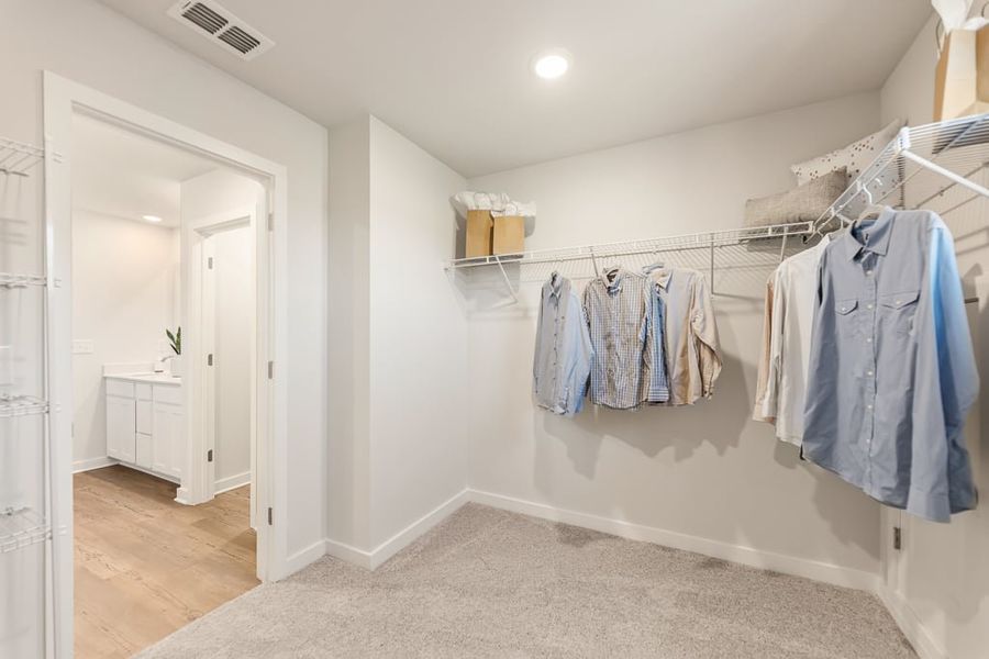 A room with a white wall and a white door with a row of clothes on it.