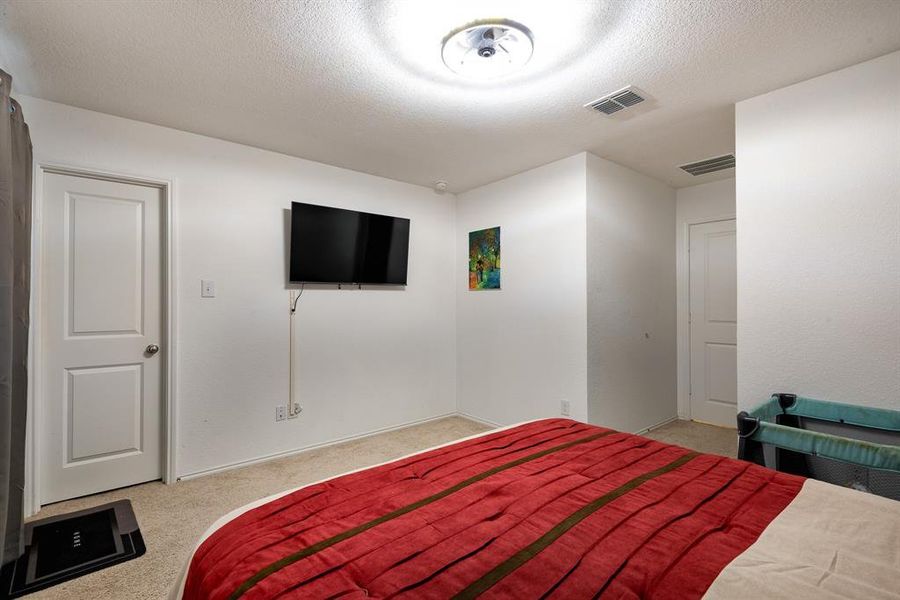 Bedroom with a textured ceiling and light carpet