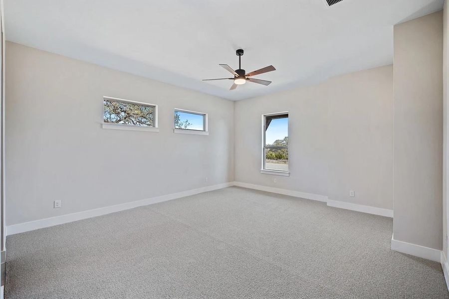 Carpeted empty room with a ceiling fan and baseboards Carpeted empty room with a ceiling fan and baseboards