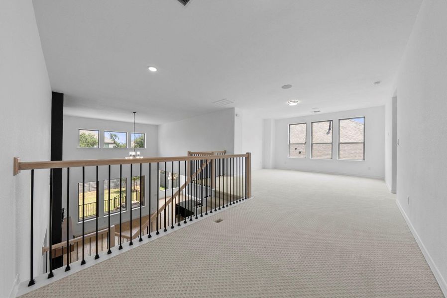 Open upstairs loft area with railing overlooking the living room, ideal for a secondary living space or game room.
