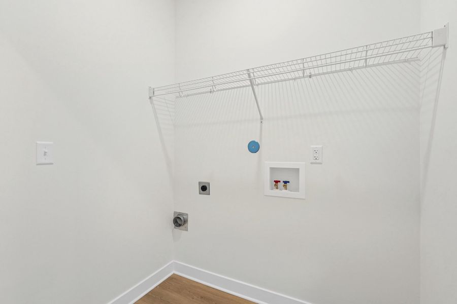 Dedicated laundry area featuring a wire rack, wood-finish flooring, and crisp white walls