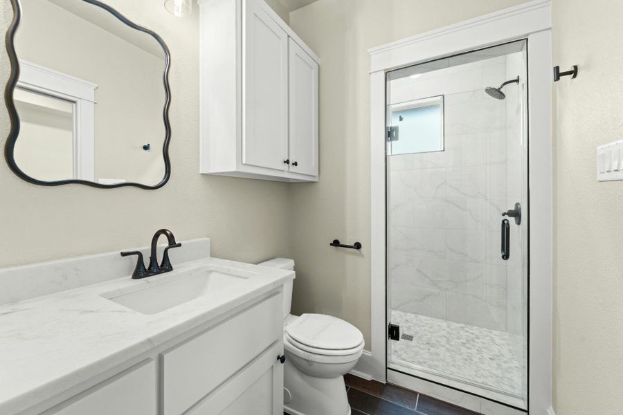 Contemporary bathroom featuring a white vanity with an integrated sink, a quartz-finish countertop, and a dark bronze faucet
