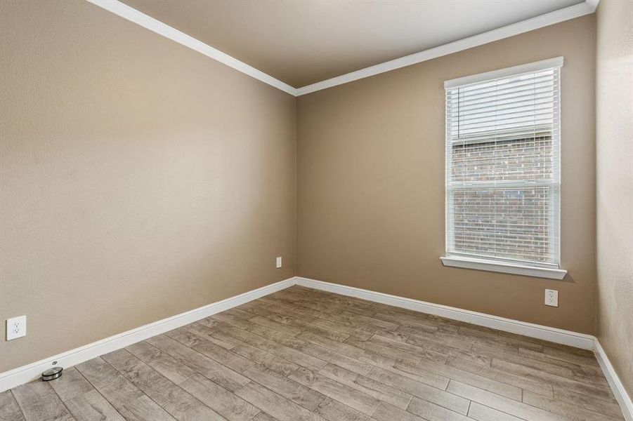 Well-lit interior space featuring wood-finish flooring, neutral wall tones, and white trim
