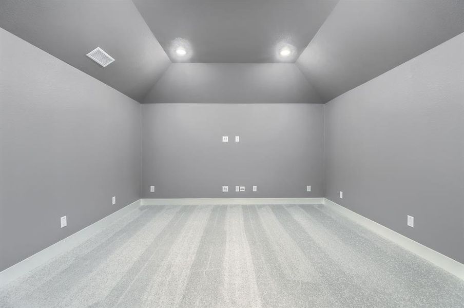 Carpeted empty room featuring lofted ceiling