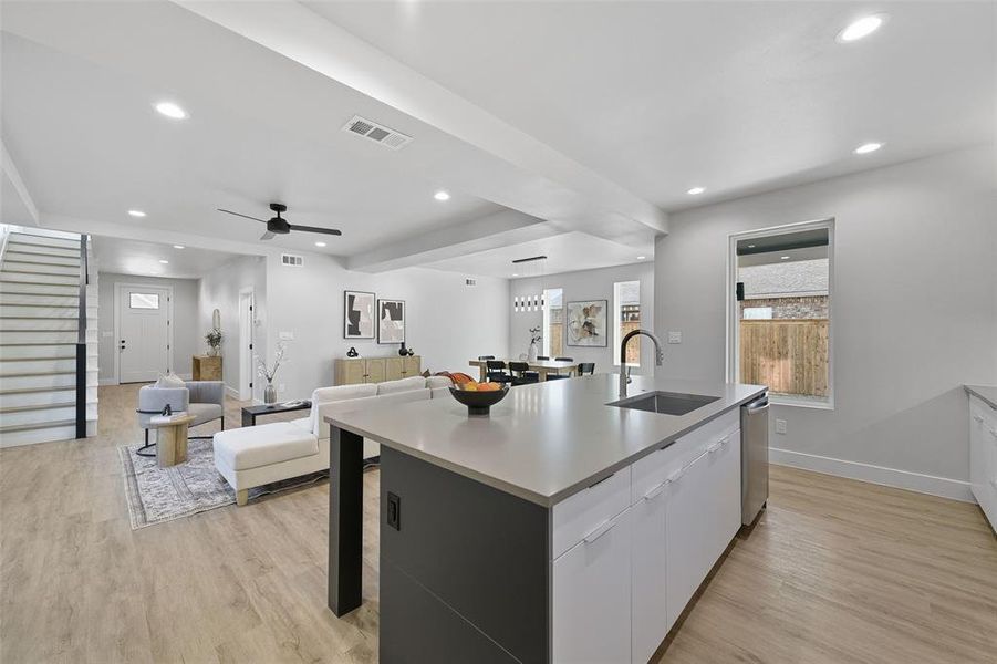 Kitchen featuring white cabinets, an island with sink, sink, light wood-type flooring, and ceiling fan