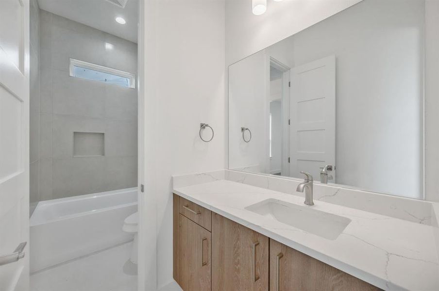 Full bath featuring vanity, toilet, and tub / shower combination Full bath featuring vanity, toilet, and tub / shower combination