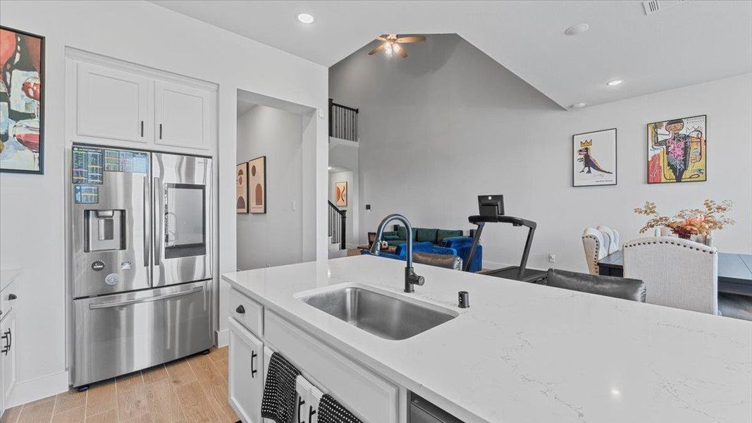 Kitchen featuring stainless steel refrigerator with ice dispenser, white cabinetry, light wood-style floors, light stone countertops, and recessed lighting Kitchen featuring stainless steel refrigerator with ice dispenser, white cabinetry, light wood-style floors, light stone countertops, and recessed lighting