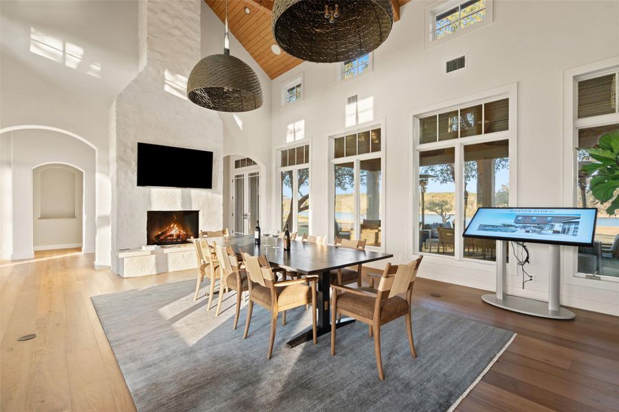 Dining area featuring wood-type flooring, arched walkways, a fireplace, a towering ceiling, and wood ceiling