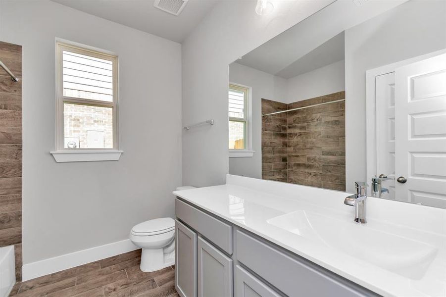 Indulge in refined charm in the secondary bathroom, where the tile flooring harmonizes with a bath/shower combo surrounded by tasteful tile. Light wood cabinets, coupled with a gorgeous countertop, elevate the space, cultivating a truly welcoming atmosphere. Sample photo of completed home. Actual colors and selections may vary.