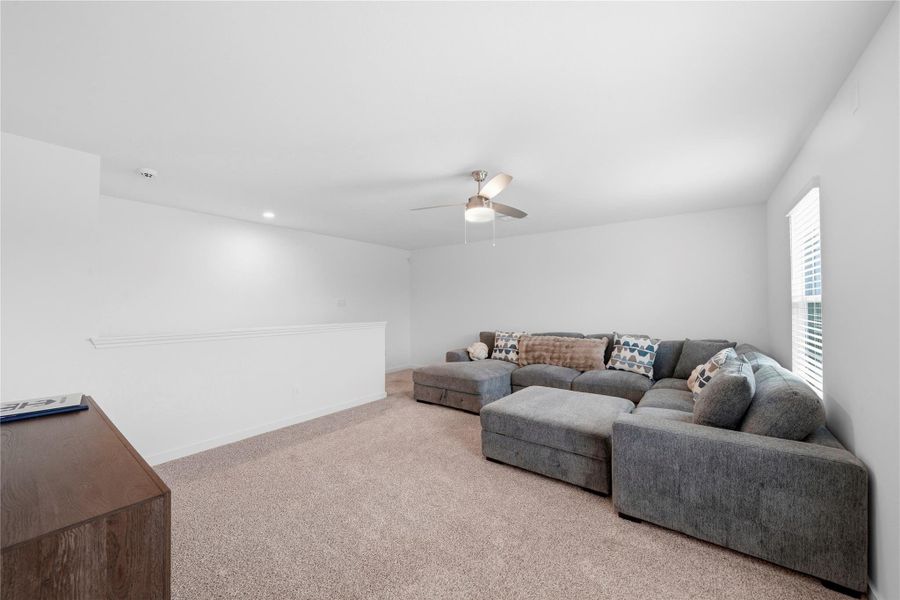 Another view of the spacious second-floor game room highlights plush carpeting, a ceiling fan for added comfort, and large windows that bring in abundant natural light. Another view of the spacious second-floor game room highlights plush carpeting, a ceiling fan for added comfort, and large windows that bring in abundant natural light.