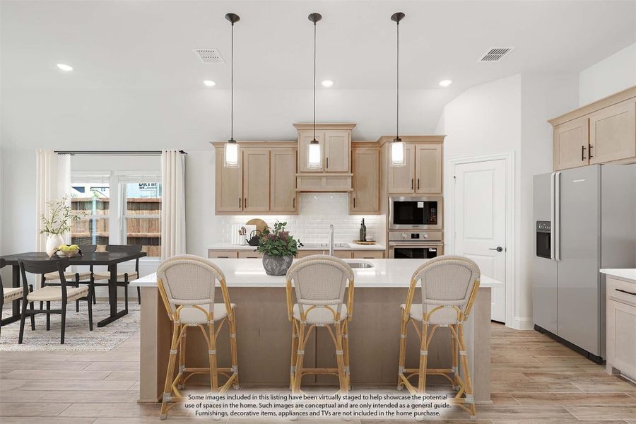 Kitchen with large island, three bar stools, light wood cabinets, pendant lights, and stainless steel appliances