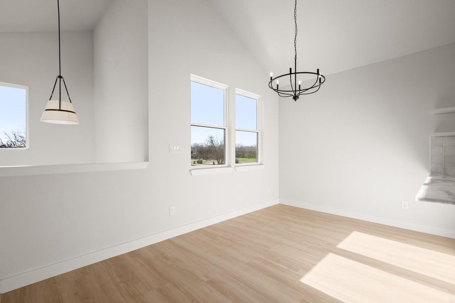 Unfurnished dining area with suspended lighting, light wood finished floors, and vaulted ceiling
