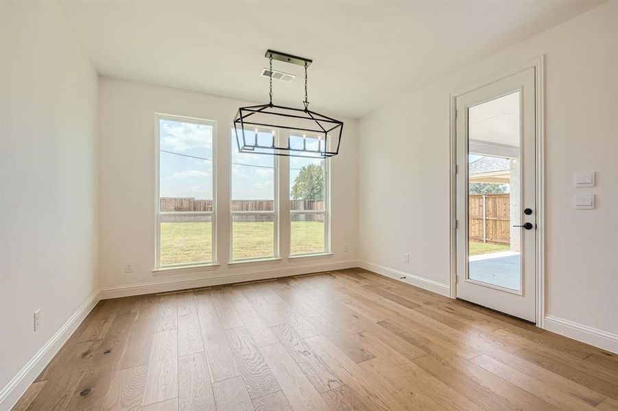 Unfurnished dining area featuring plenty of natural light, a chandelier, and light hardwood / wood-style flooring