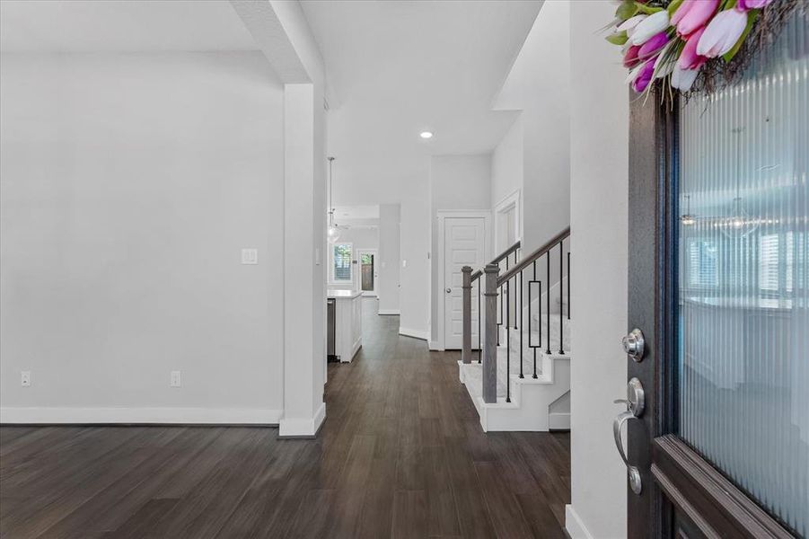 Cozy front entryway featuring a wood door with glass panels, adorned with a colorful wreath. The covered porch area is complemented by neutral siding!