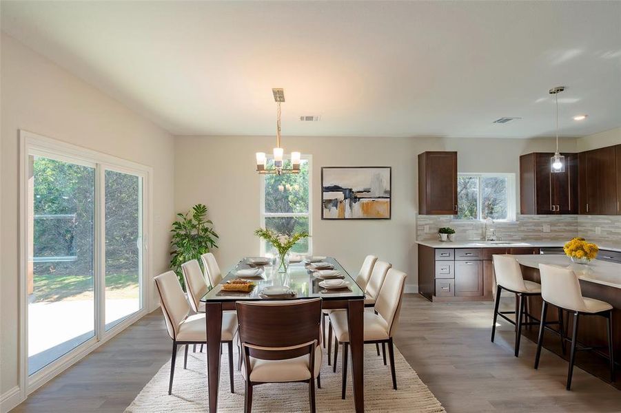 Dining space with light wood-type flooring, sink, and an inviting chandelier