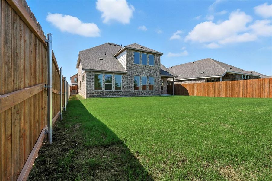 Back of house featuring a fenced backyard, a shingled roof, brick siding, and a patio area