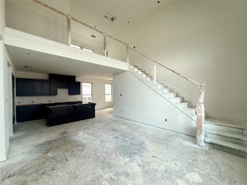 A family room with high ceilings, bright windows, and a banister staircase, open to the kitchen, creates a spacious and welcoming place to gather and entertain. A family room with high ceilings, bright windows, and a banister staircase, open to the kitchen, creates a spacious and welcoming place to gather and entertain.