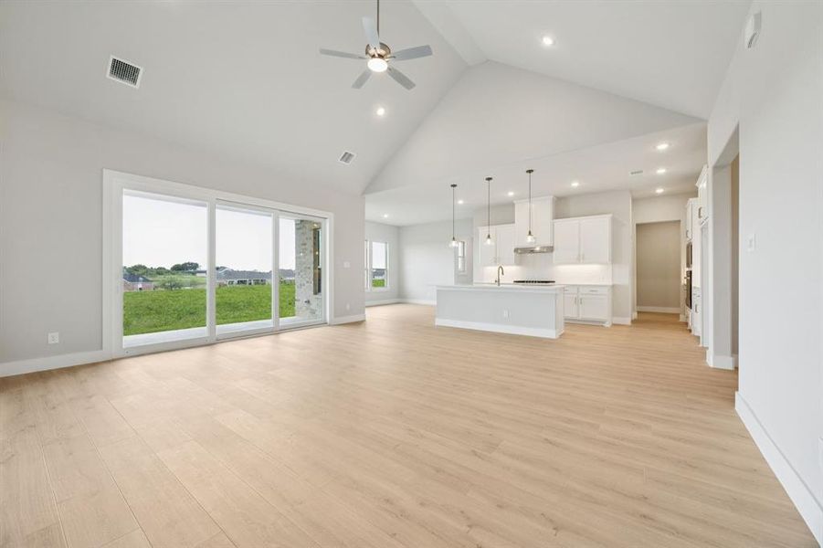 Unfurnished living room with high vaulted ceiling, light wood finished floors, recessed lighting, and a ceiling fan