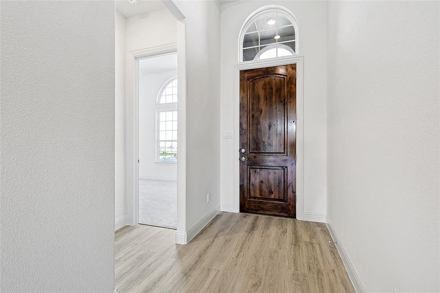 Entryway with light wood finished floors and a textured wall