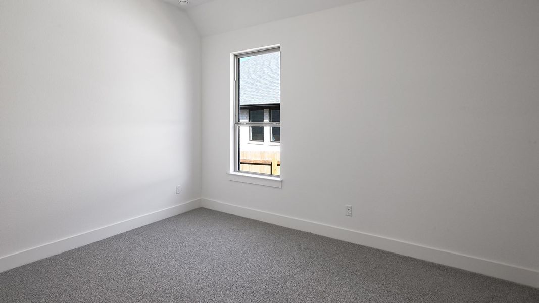 Spare room with lofted ceiling, dark carpet, and baseboards