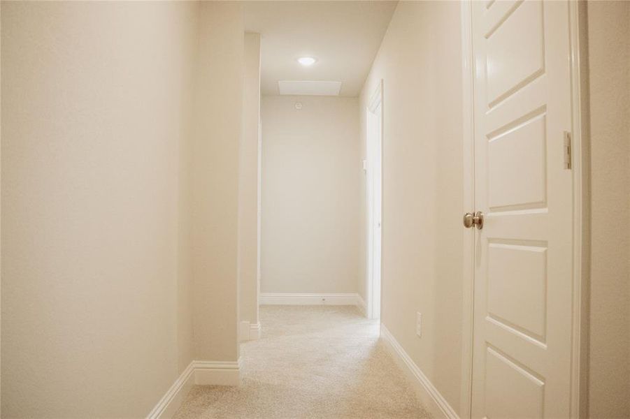 Hallway featuring light colored carpet