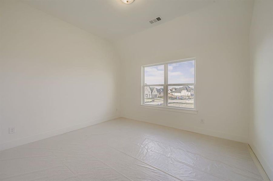 Spare room featuring lofted ceiling and baseboards