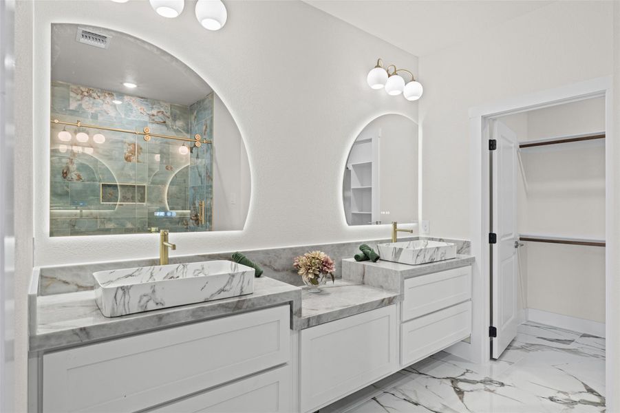 Gleaming marble flooring and double vessel sinks define this contemporary primary bath oasis.