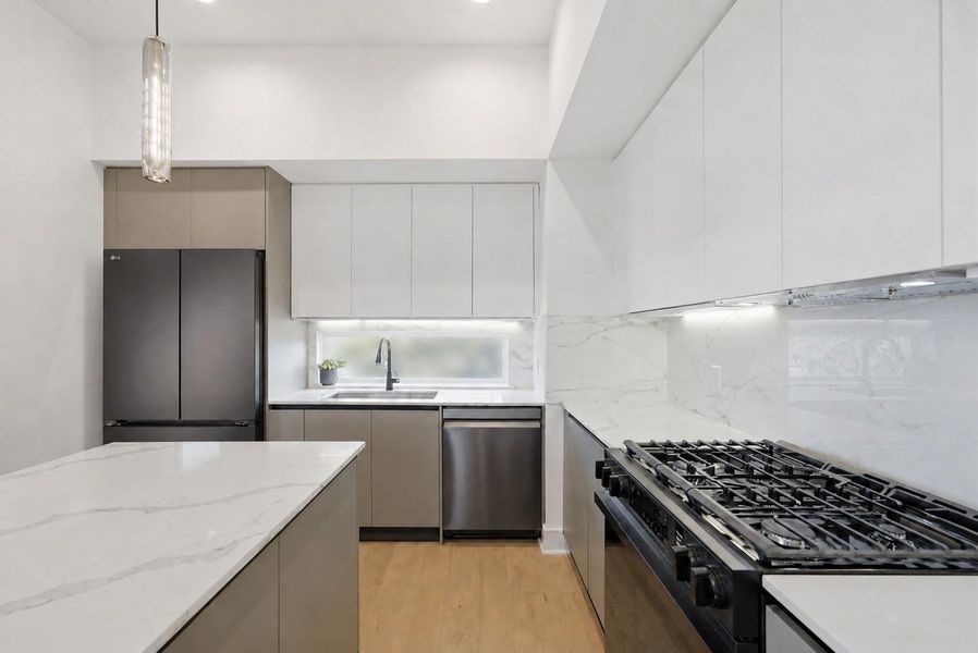 This elegant kitchen features sophisticated European-style cabinets with soft close drawers sleek, minimalist lines paired with stunning quartz countertops for a modern luxury and timeless appeal.